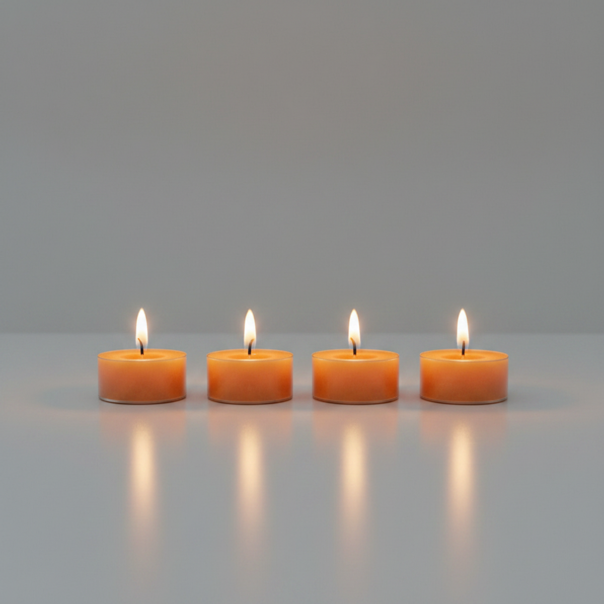 Four pleasantly lit LorJas Handmade lightly scented soy candles with gray studio background with a warm ambient glow.