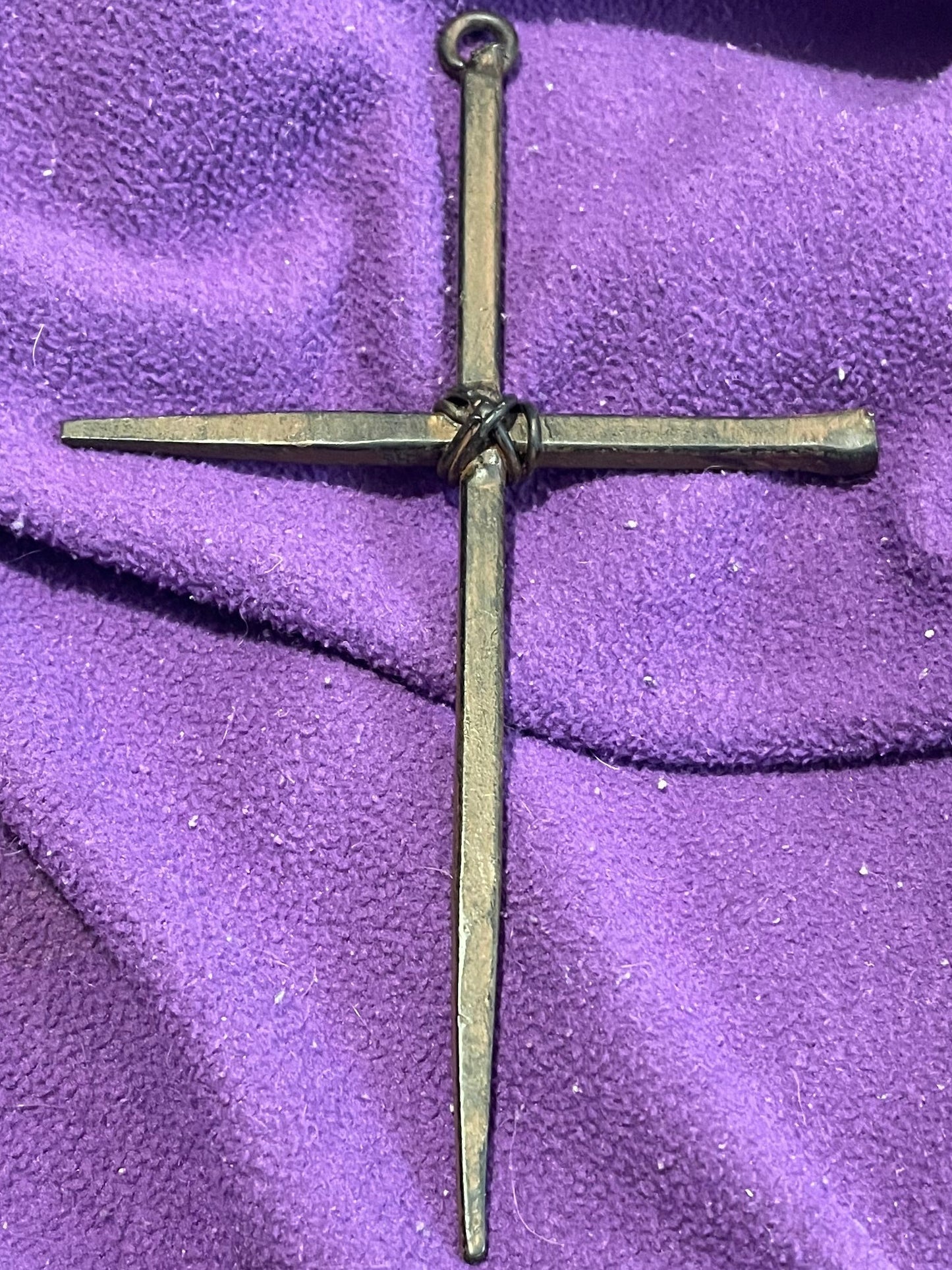 Bronze cross on a purple fabric background