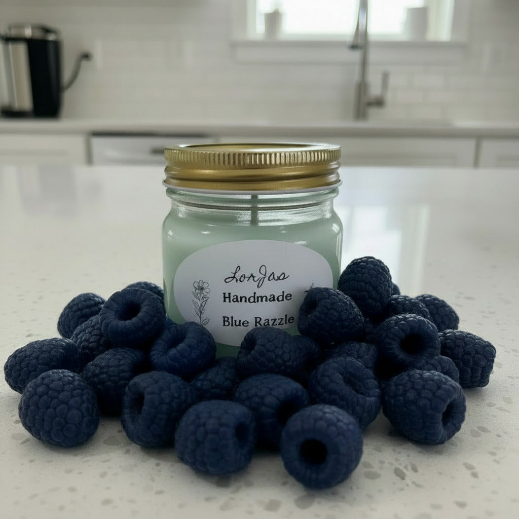 LorJas Handmade Blue Razzle lightly scented soy candle on marble counter beside fresh blue raspberries with blurred kitchen background.