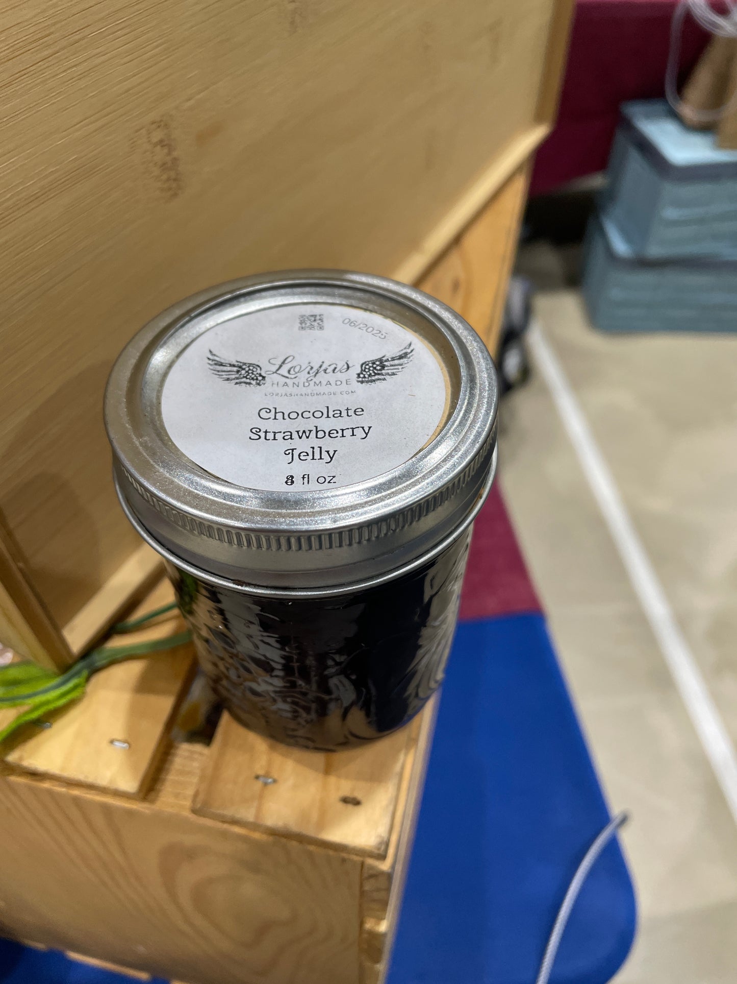 Jar of LorJas Handmade 'Chocolate Strawberry' jelly at market on a wooden surface