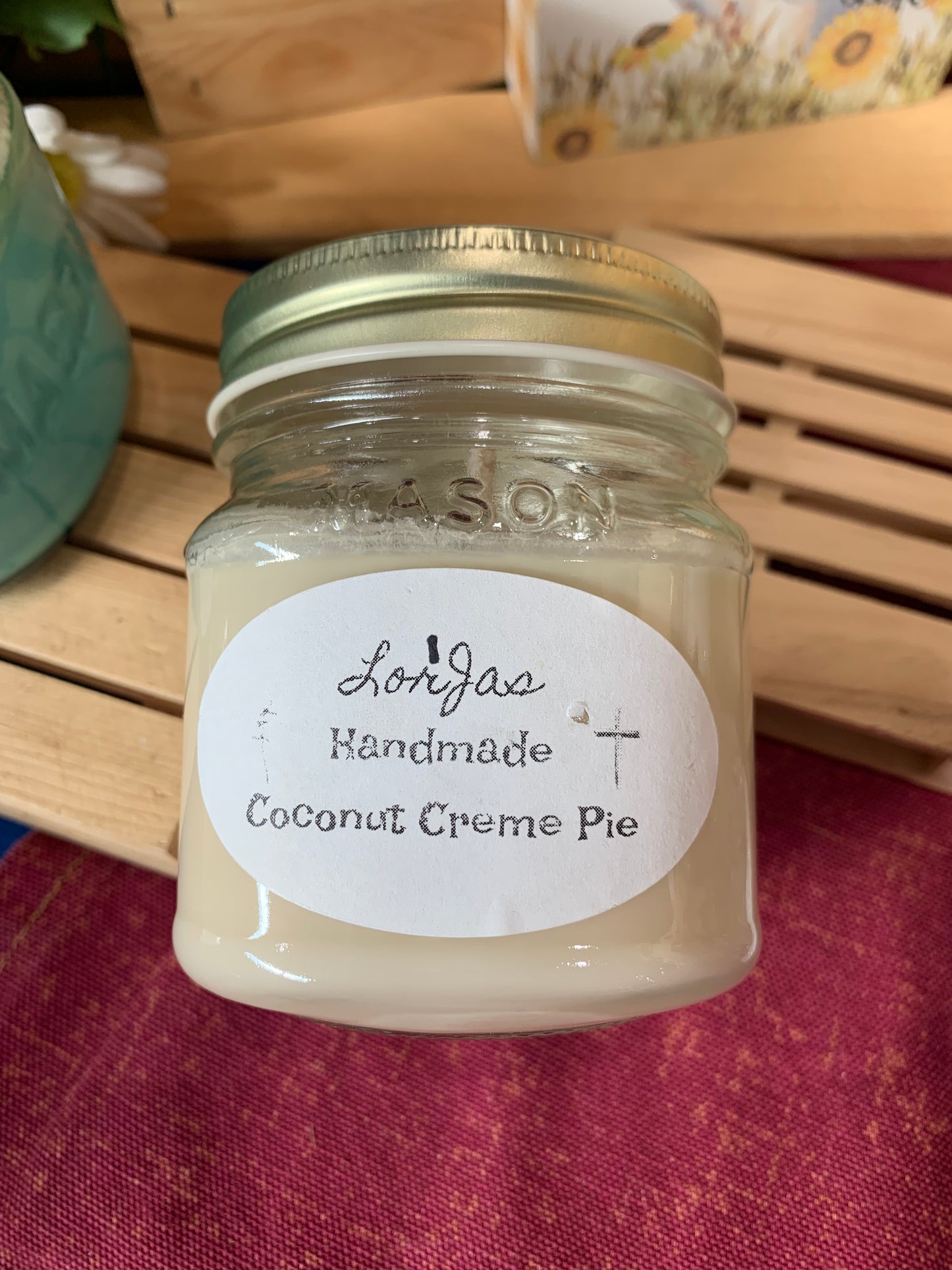 Jar of LorJas Handmade 'Coconut Crème Pie' scented organic soy candle on a wooden surface with a branded label.