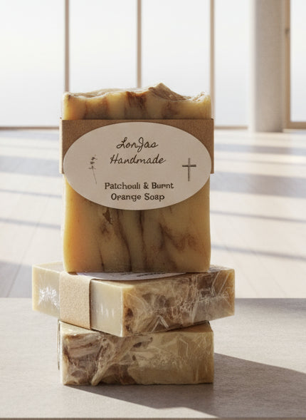 Stack of LorJas Handmade 'Patchouli & Burnt Orange' scented organic Castile soap bars with a visible label on a light background