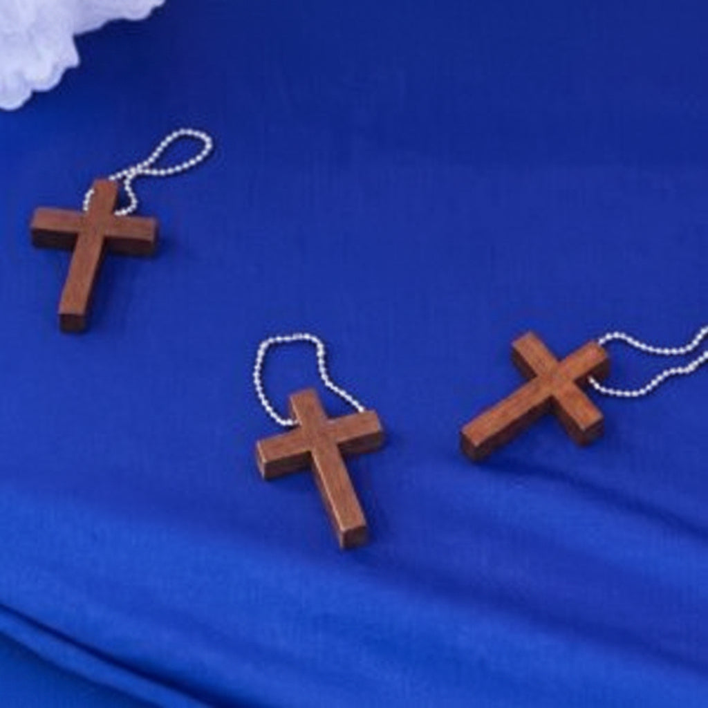 Three wooden crosses on keychains on a blue fabric table background