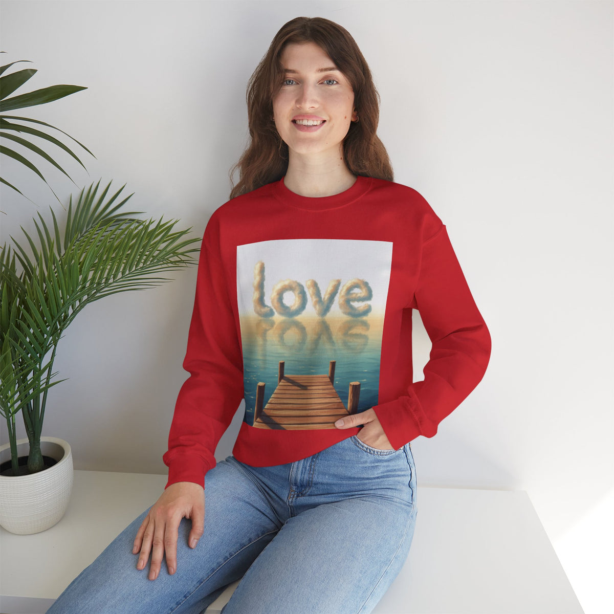 Person wearing a red sweatshirt with a 'love' graphic design sitting on a white surface.