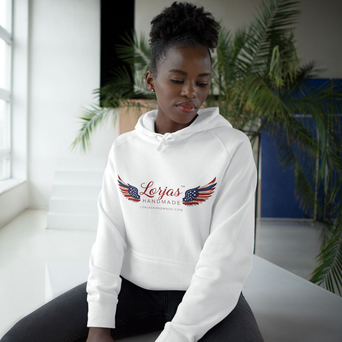 Person wearing a white hoodie with a logo sitting indoors.
