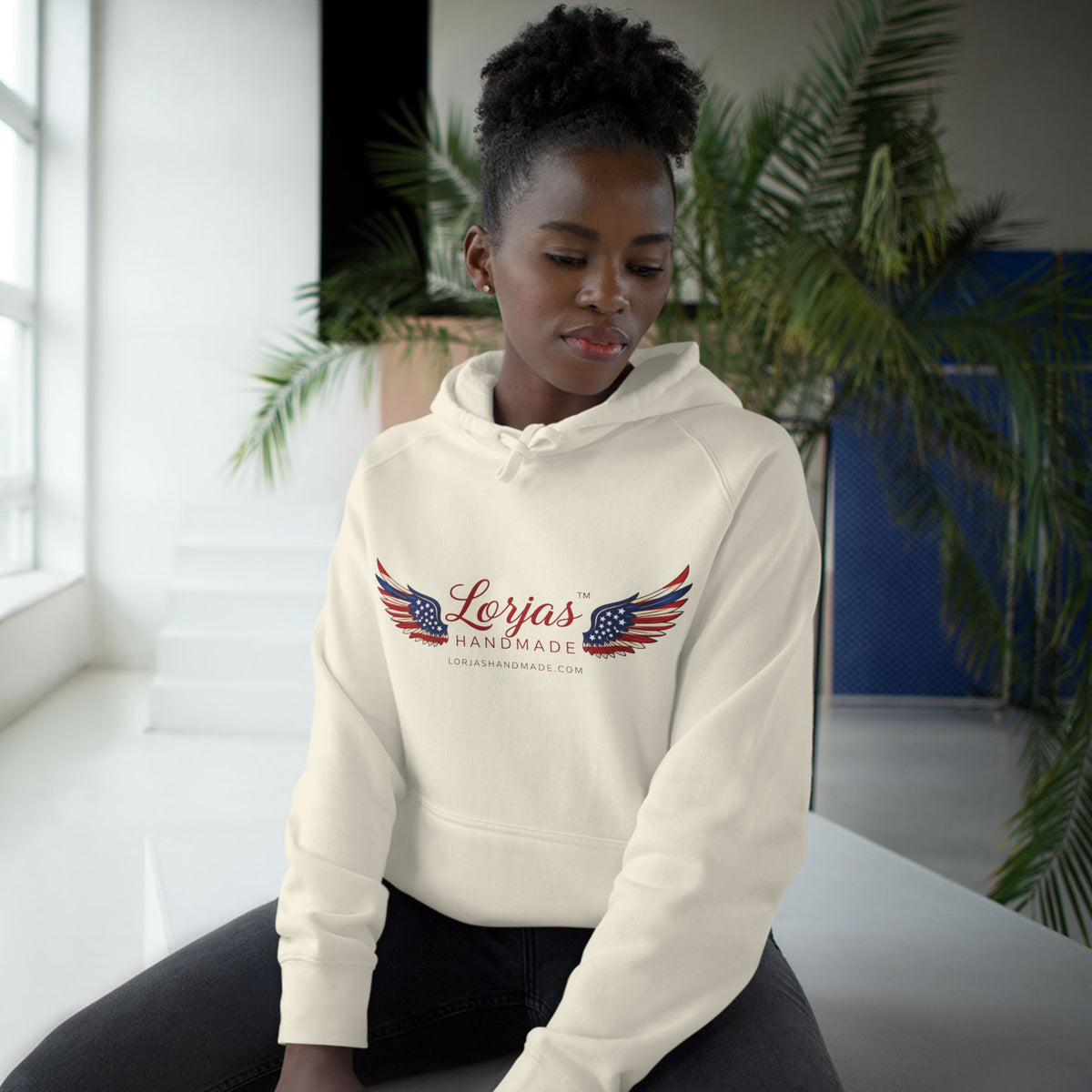 Person wearing a cream hoodie with 'Lorjas Handmade' logo in an indoor setting.