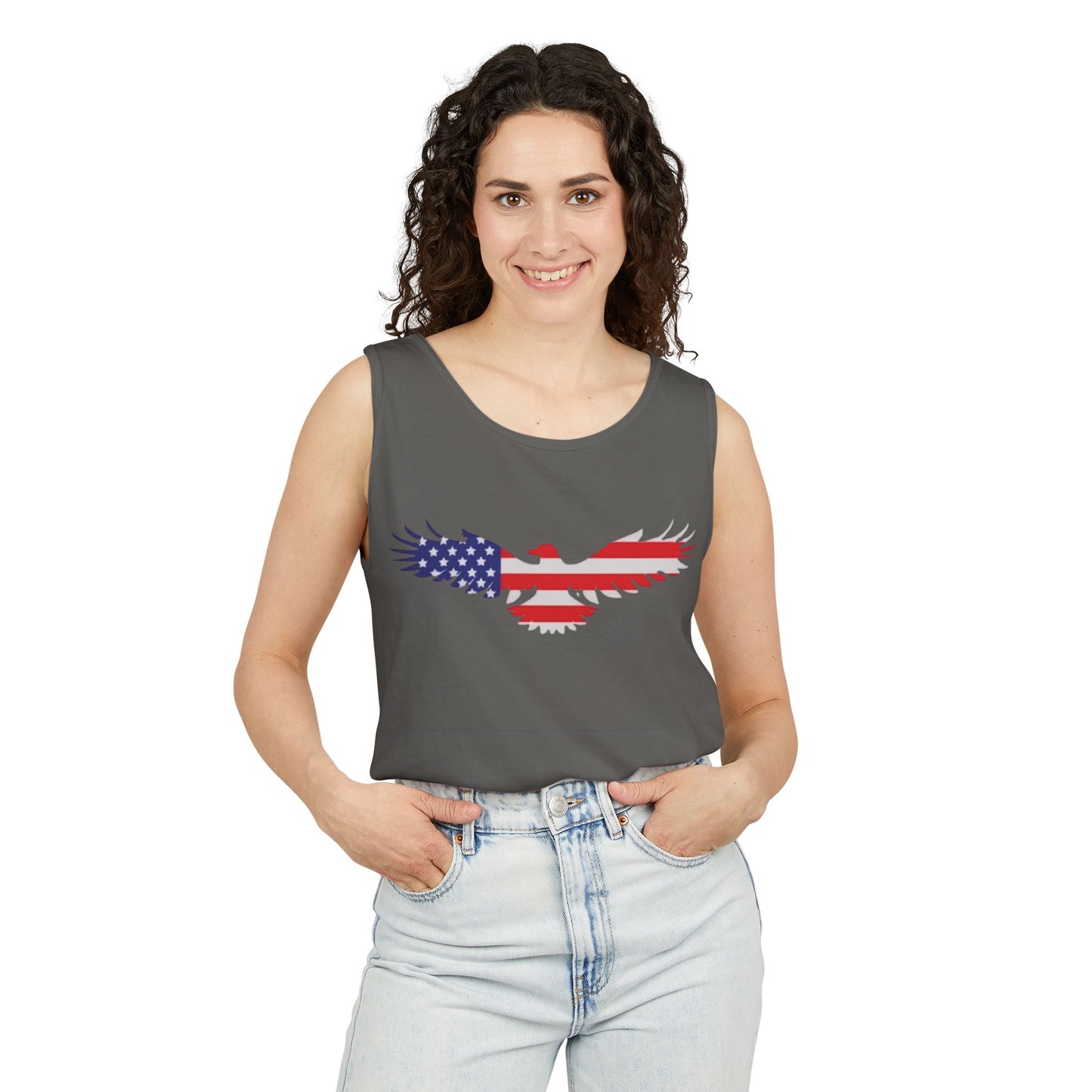 A woman with curly dark hair wearing a dark gray sleeveless tank top with a red, white, and blue eagle graphic, paired with light-wash jeans, against a plain white background.