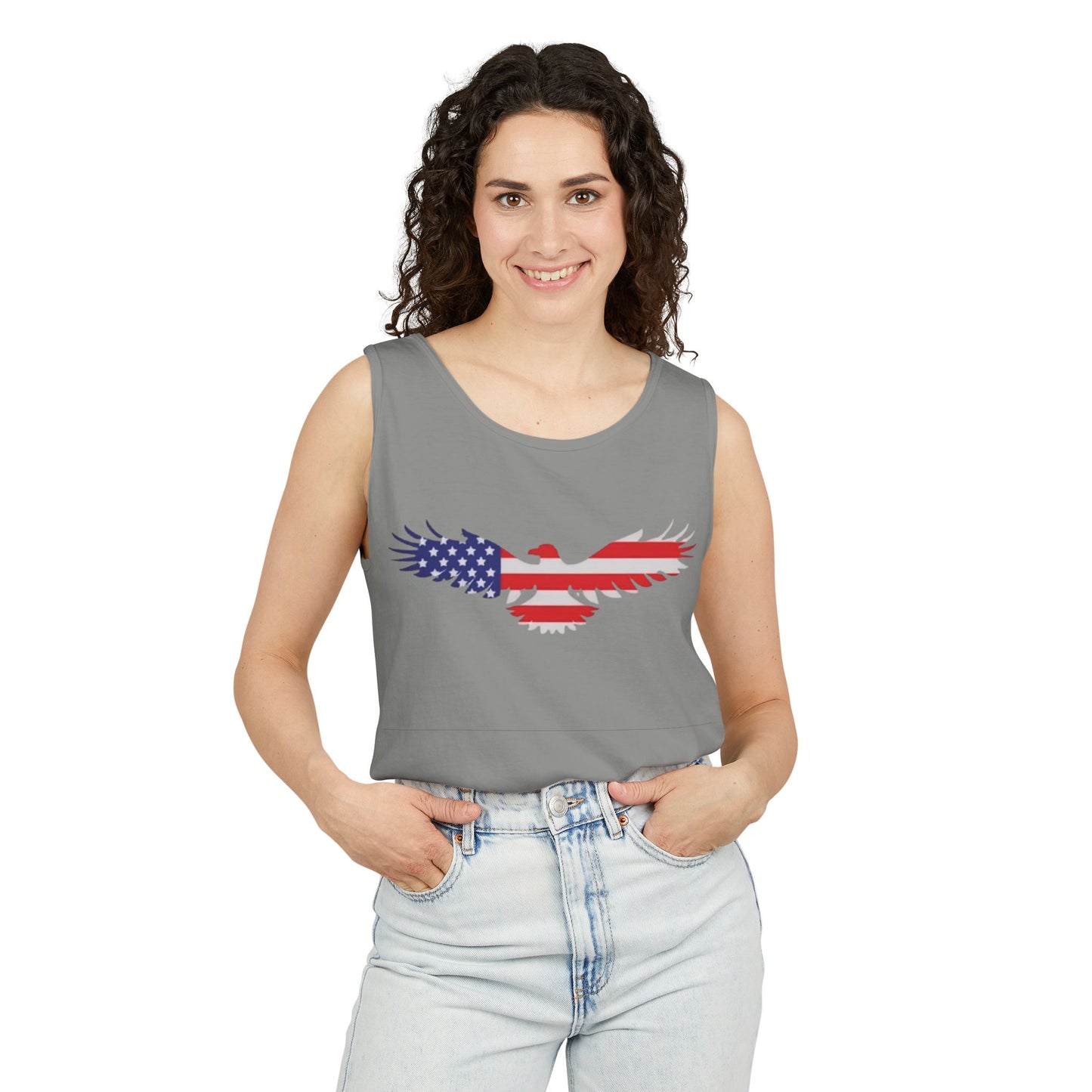 A woman modeling a gray sleeveless crop top with a graphic of a bird wing filled with the American flag pattern, paired with light-wash jeans against a plain white background.