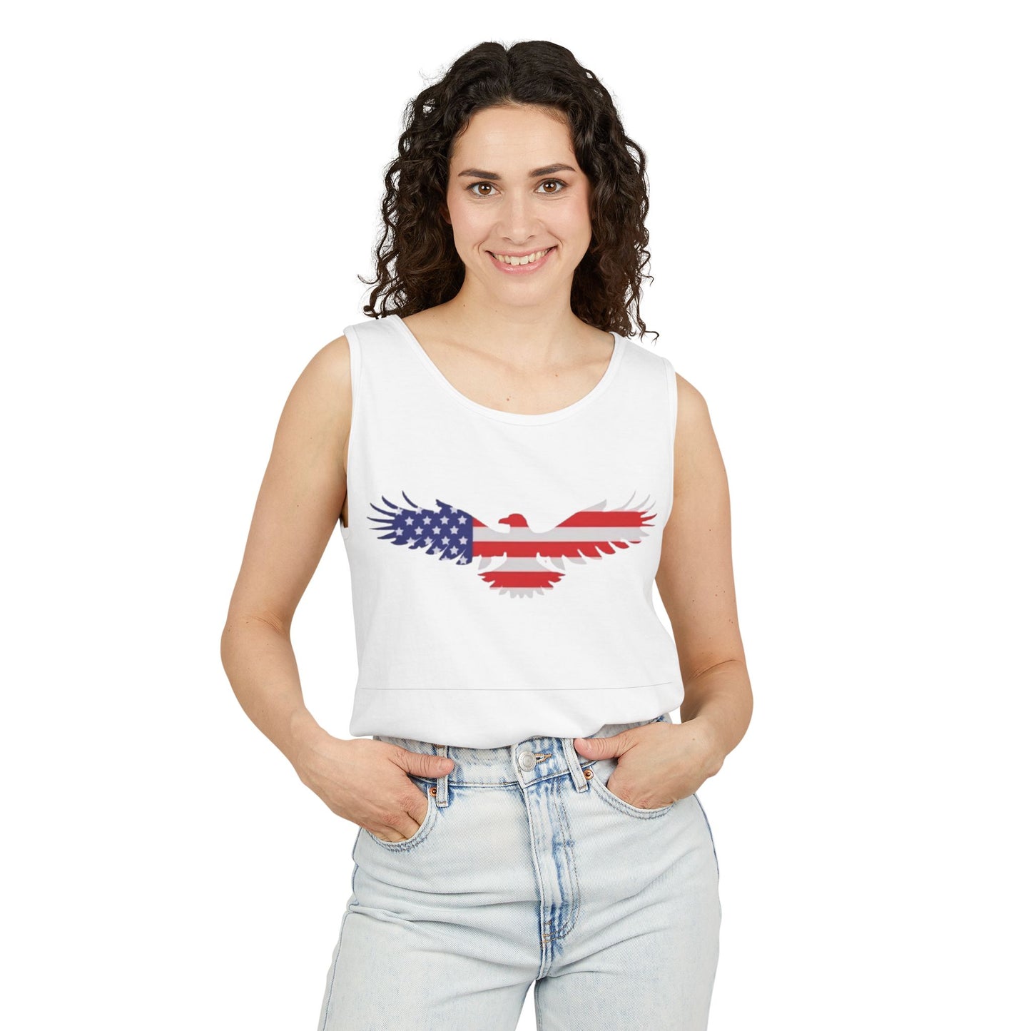 A woman modeling a white sleeveless crop top with a distressed eagle graphic filled with the American flag pattern, paired with light-wash jeans against a plain white background.