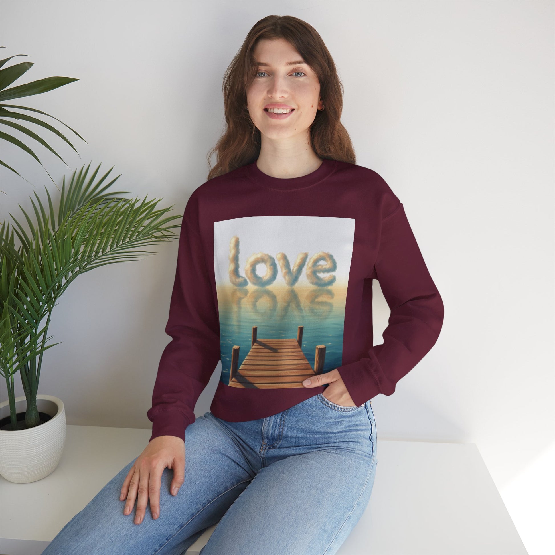 Woman wearing a maroon sweatshirt with 'love' and 'rope' design, sitting on a white surface with a plant in the background.