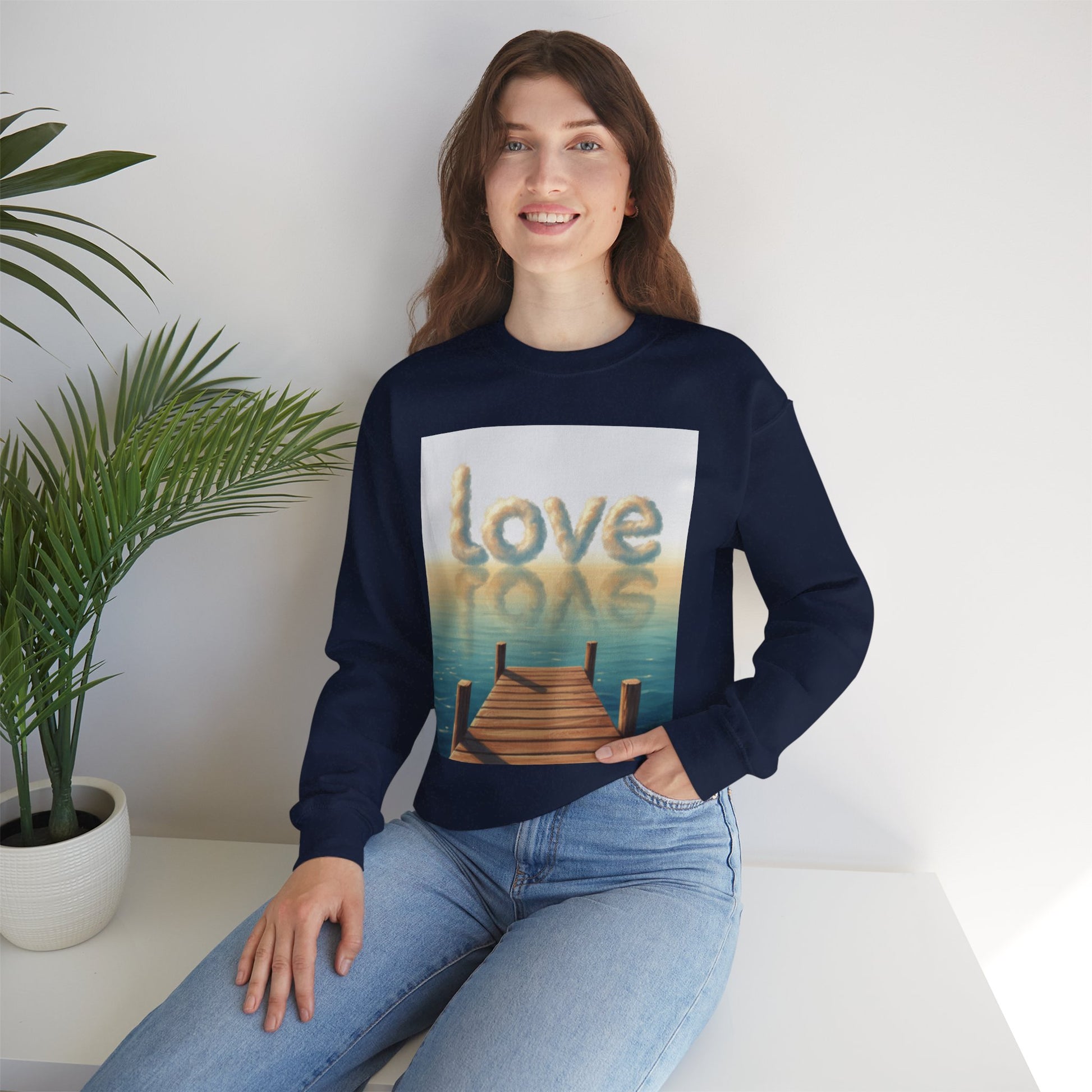 Person wearing a navy blue sweatshirt with a 'love' graphic design, sitting on a white surface with a plant in the background.