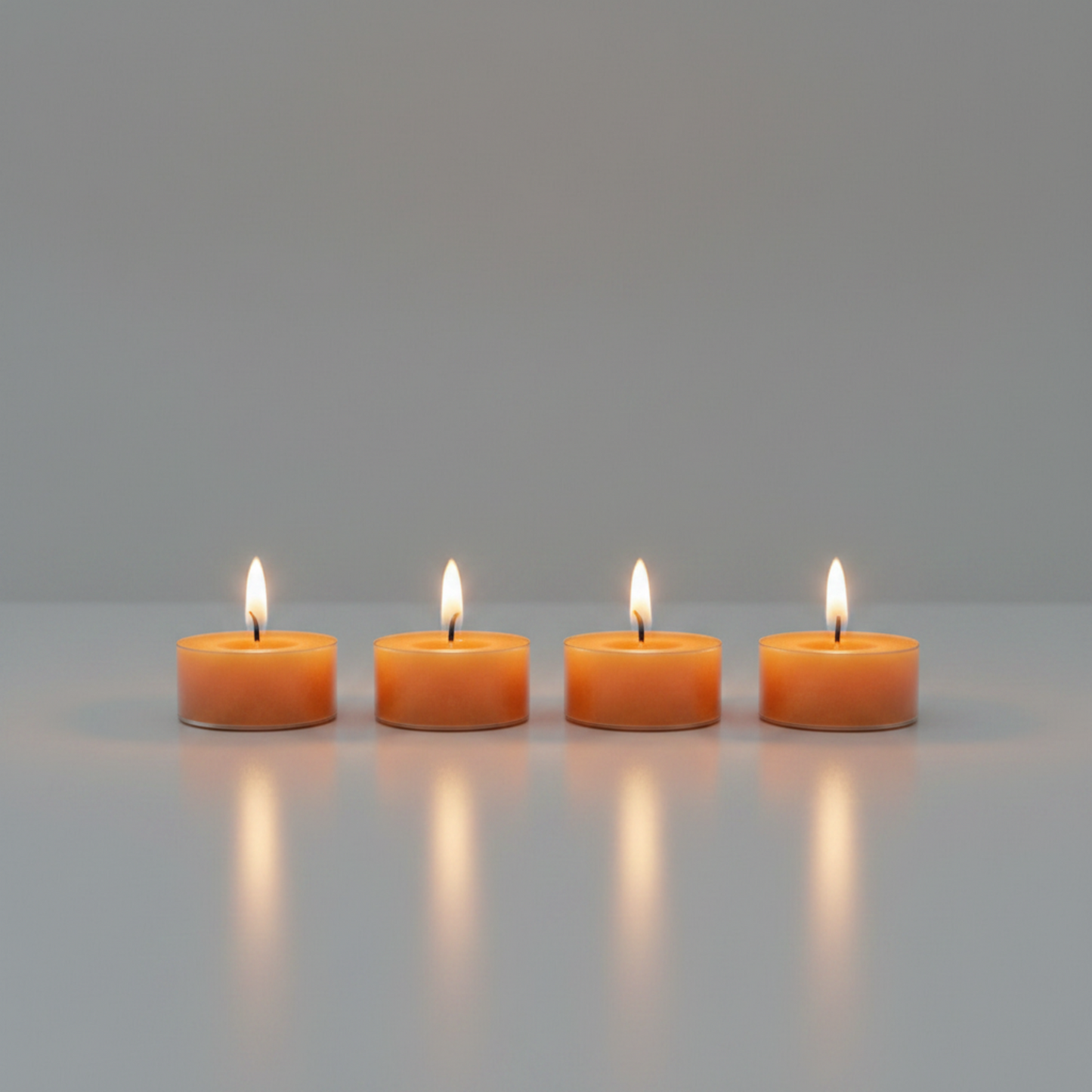 Four pleasantly lit LorJas Handmade lightly scented soy candles with gray studio background with a warm ambient glow.