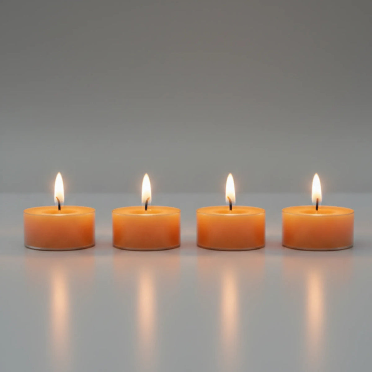 Four pleasantly lit LorJas Handmade lightly scented soy candles with gray studio background with a warm ambient glow.