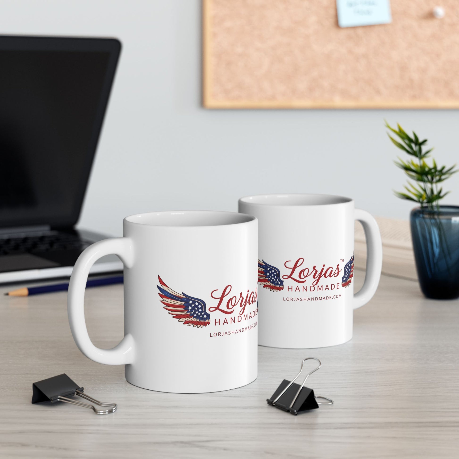 Two white mugs with 'Lorjas Handmade' logo on a desk with office supplies.