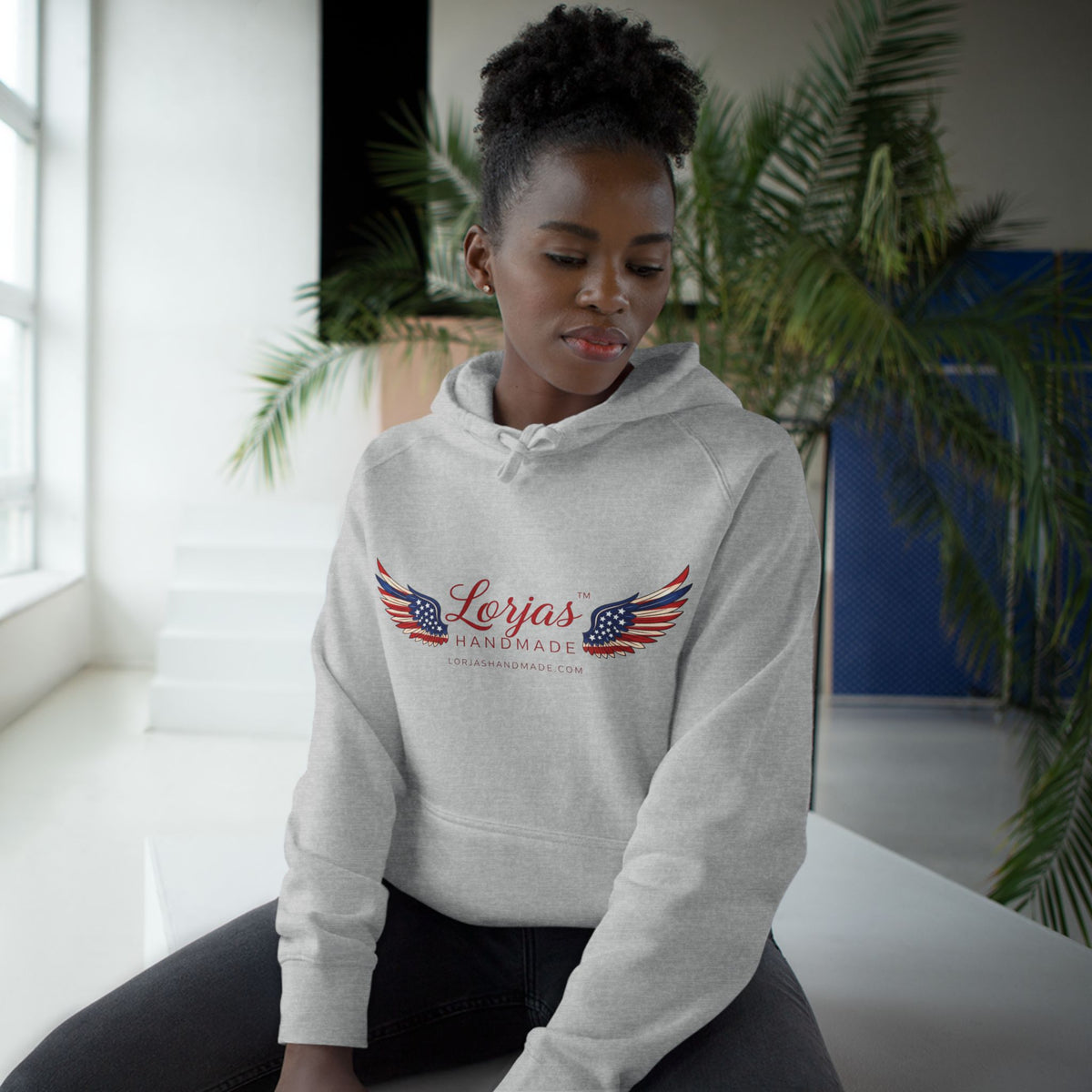 Person wearing a gray hoodie with 'What's for dinner?' text in a room with plants.