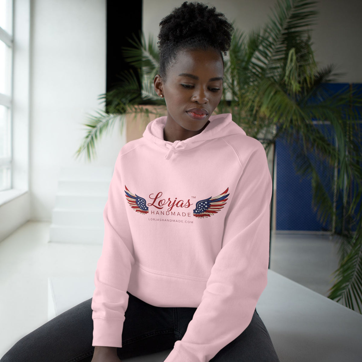 Person wearing a pink hoodie with 'always' text in a modern indoor setting