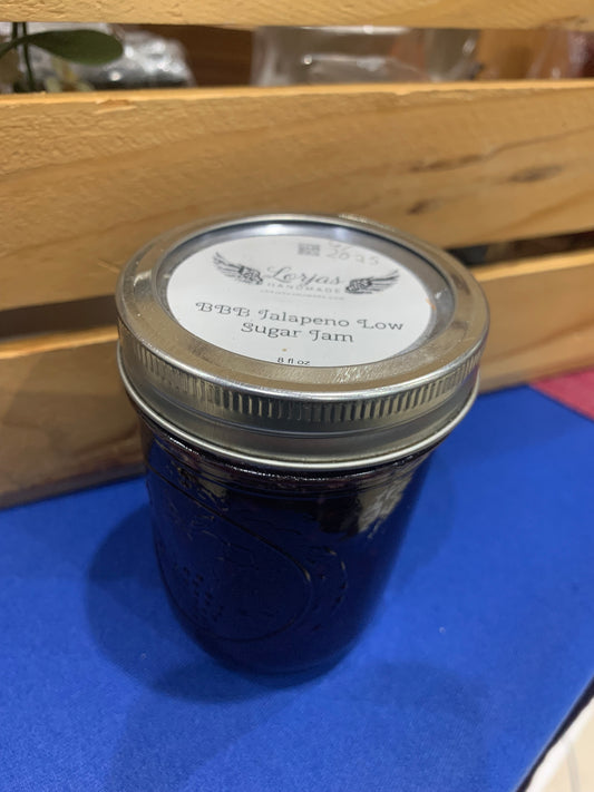 Jar of LorJas Handmade 'BBB Jalapeño' pepper jelly with a label on a blue surface with wooden background