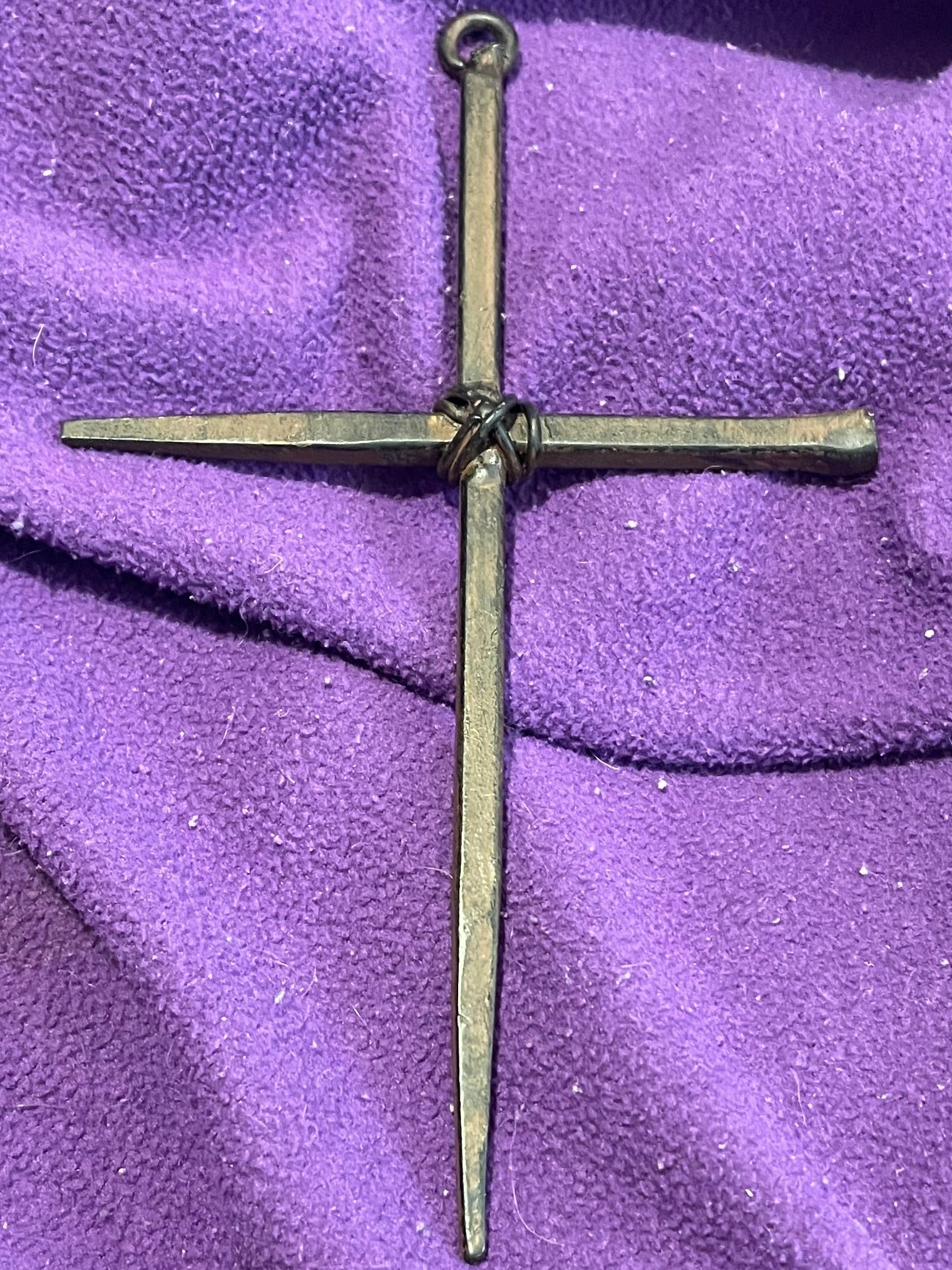 Bronze cross on a purple fabric background