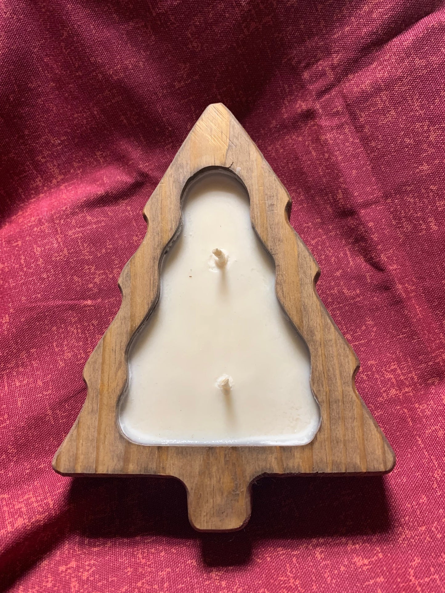 LorJas Handmade wooden tree-shaped mold filled with 'Harvest' scented organic soy white candle on a red fabric background