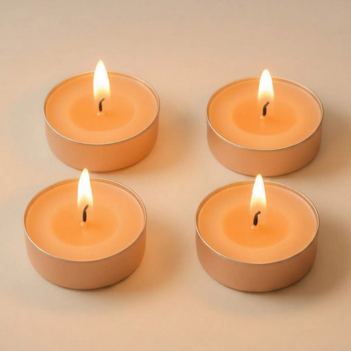 Four lit peach LorJas Handmade lightly scented soy tealights on a beige background.