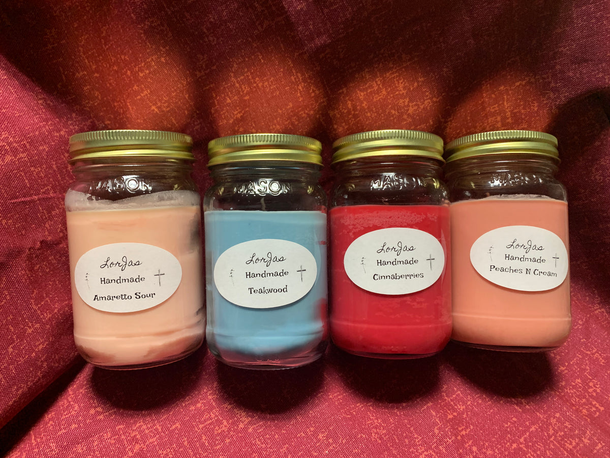Four jars of LorJas Handmade organic soy scented candles with branded labels on a red textured surface