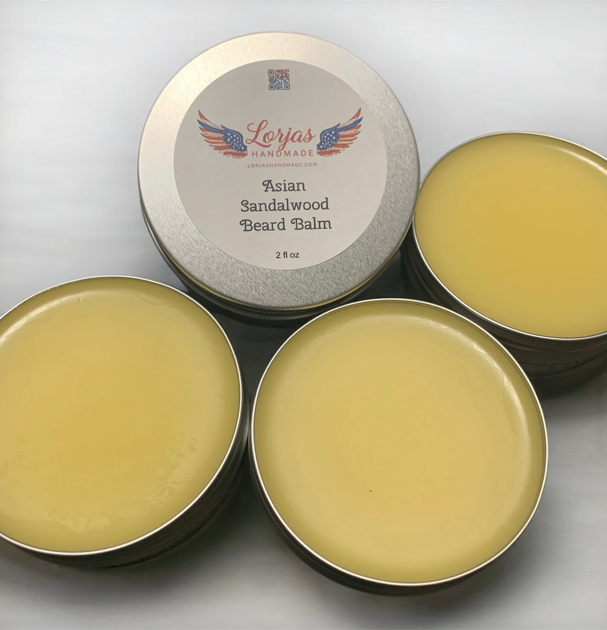 Four tins of Asian Sandalwood Beard Balm on a white canopy background.