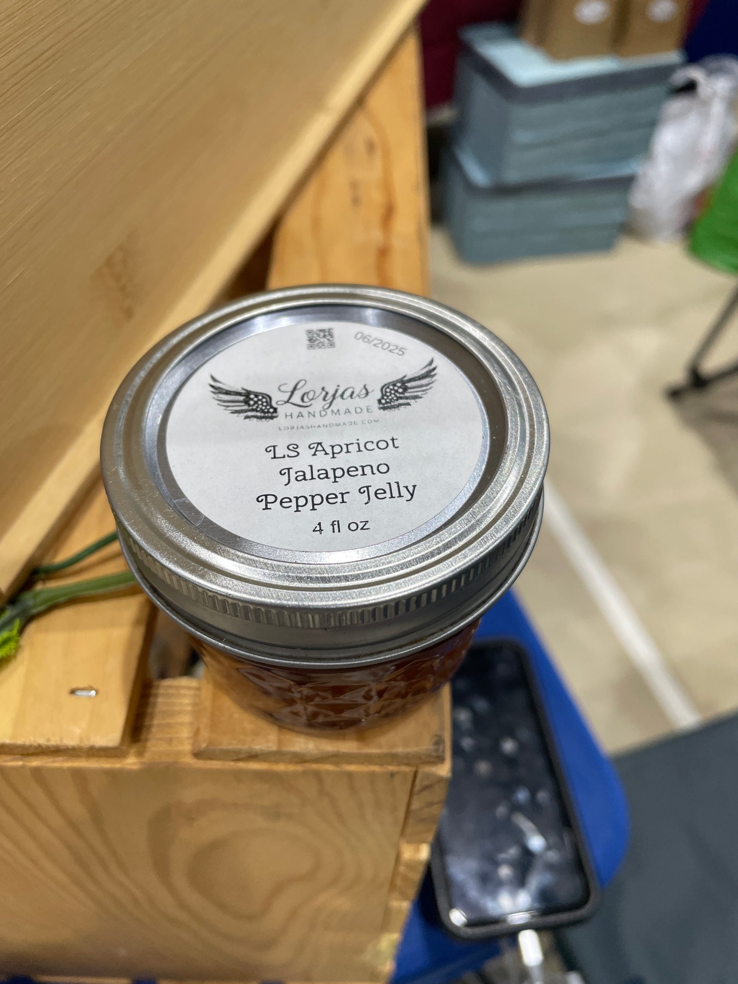 Jar of LorJas Handmade 'Apricot Jalapeño' pepper jelly with a metal lid on a wooden surface