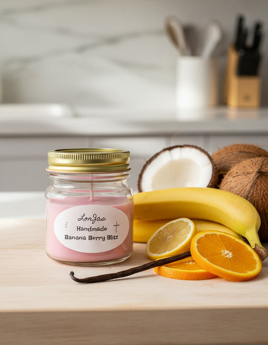 Organic soy scented candle 'LorJas Handmade Banana Berry Blitz' on countertop beside bananas, citrus, vanilla bean, and coconuts