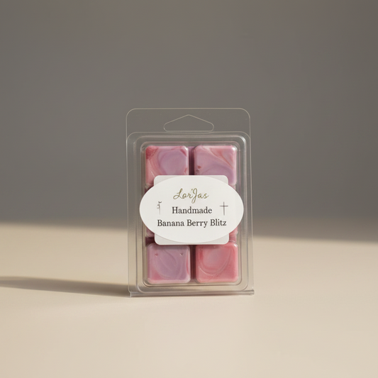 A clear clamshell package containing a lightly scented soy wax melts with a white oval label that reads 'LorJas Handmade Banana Berry Blitz' on a neutral beige and gray background.