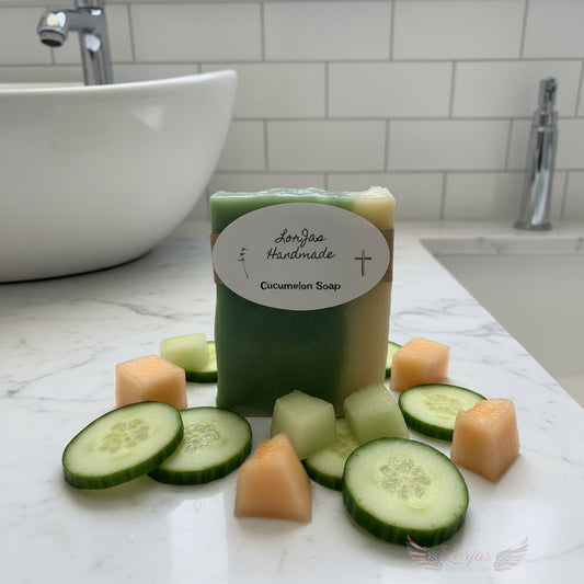 LorJas Handmade Cucumelon lightly scented Castile soap with fresh sliced melon and cucumber on a granite counter beside a wash basin and sink.