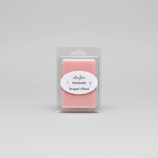 A pink wax melt in a clear plastic clamshell package with a white oval label reading 'Lor'Jas Handmade Dragon's Blood' on a light gray background.