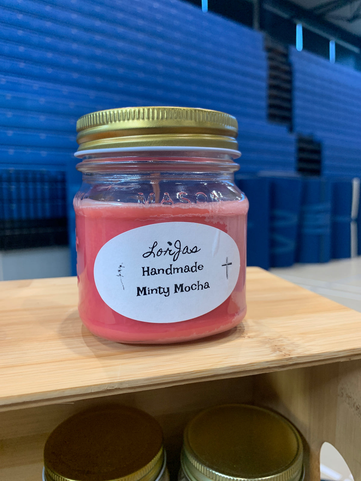 Jar of LorJas Handmade 'Minty Mocha' on a wooden surface with a blue checkered background