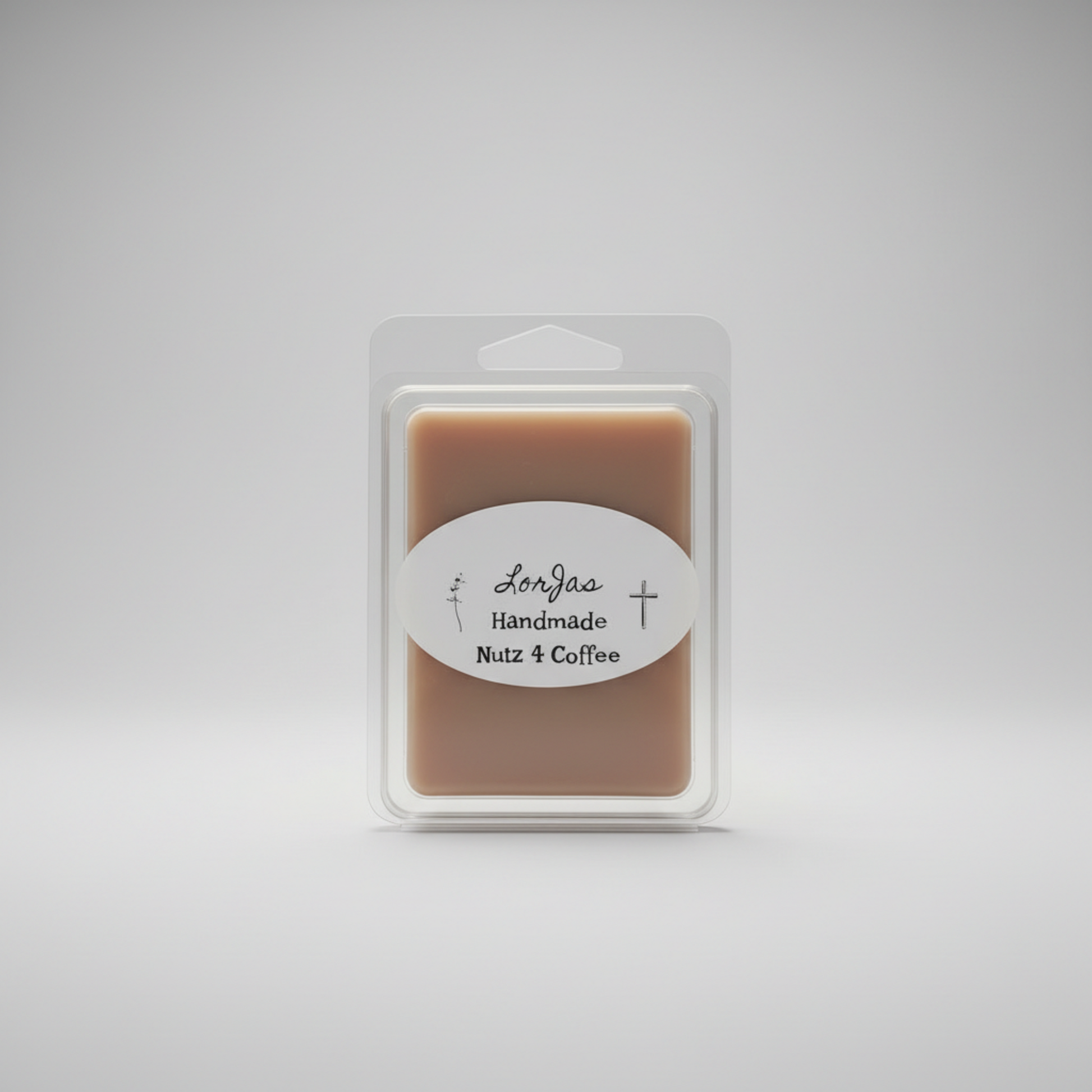A packaged wax melt in a clear plastic clamshell package on a light gray studio background. The product inside is a warm tan-brown rectangular bar with a white oval label reading LorJas Handmade 'Nutz 4 Coffee'.