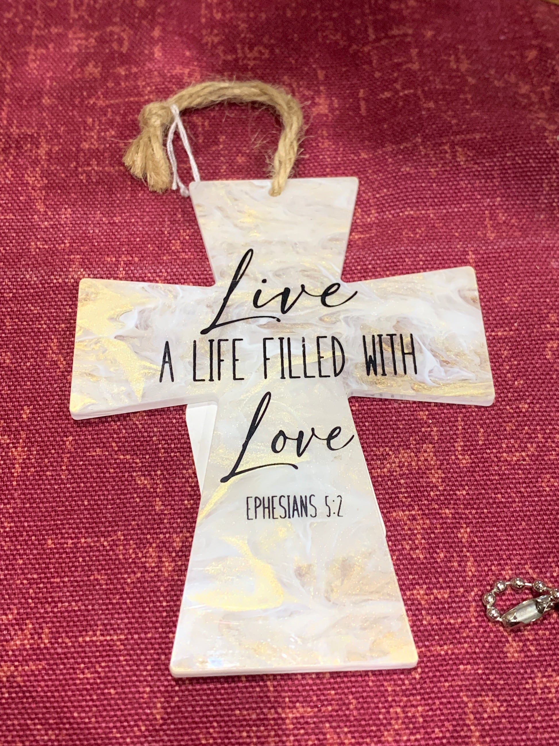 Decorative cross with 'Live a Life Filled with Love' text on a red fabric background