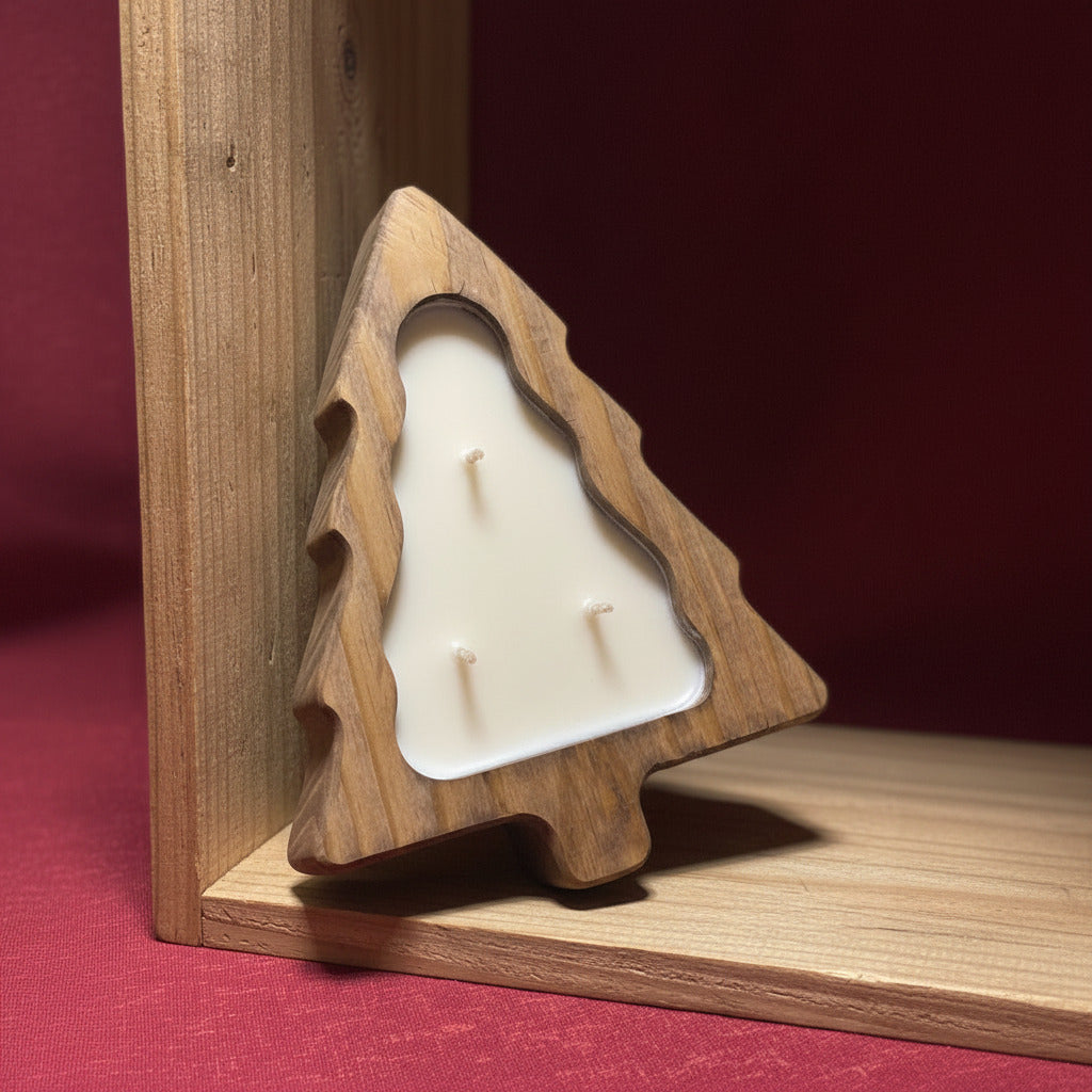 LorJas Handmade lightly scented organic soy candle in a Christmas-tree shaped wooden holder set on an angle in a wood shelf with red fabric backing.