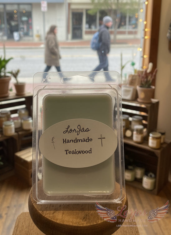 Handmade teakwood wax melt in plastic packaging on a wooden surface with a store interior background.