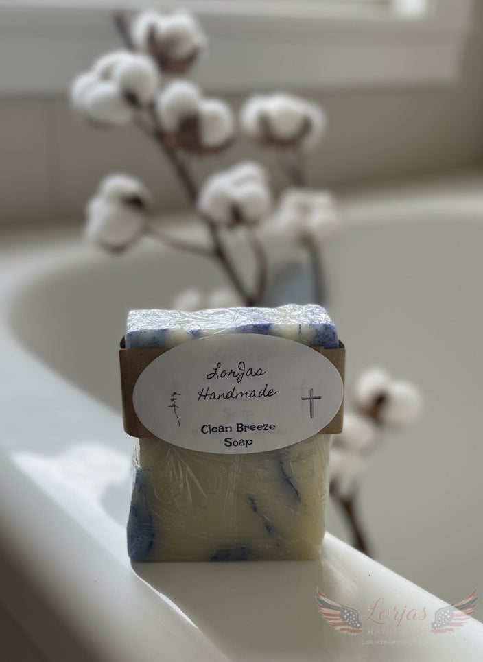 LorJas Handmade 'Clean Breeze' scented organic Castile soap on side of antique standing tub with a single stem of a cotton plant in the background 