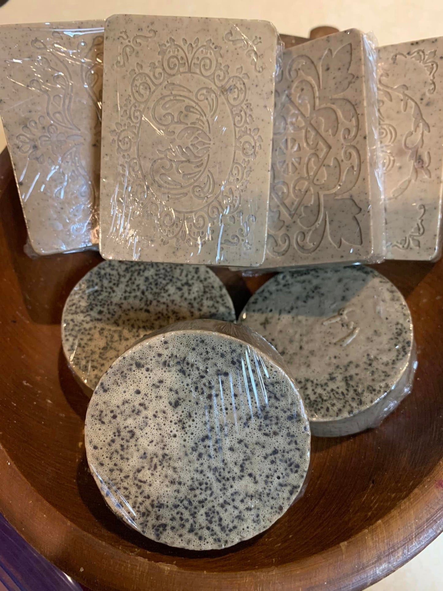 Several bars of LorJas Handmade 'Coffee' scented organic goat milk soap in wooden display bowl with beige background