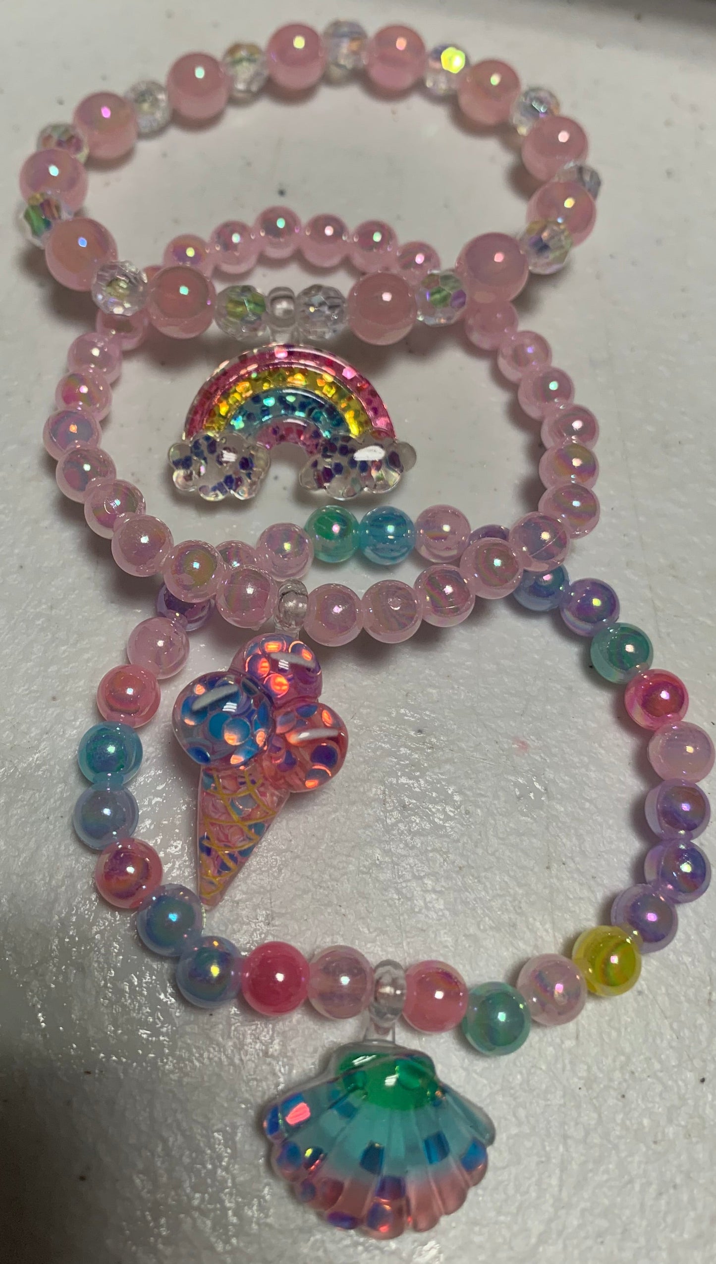 Three colorful beaded childrens' bracelets set on a white surface