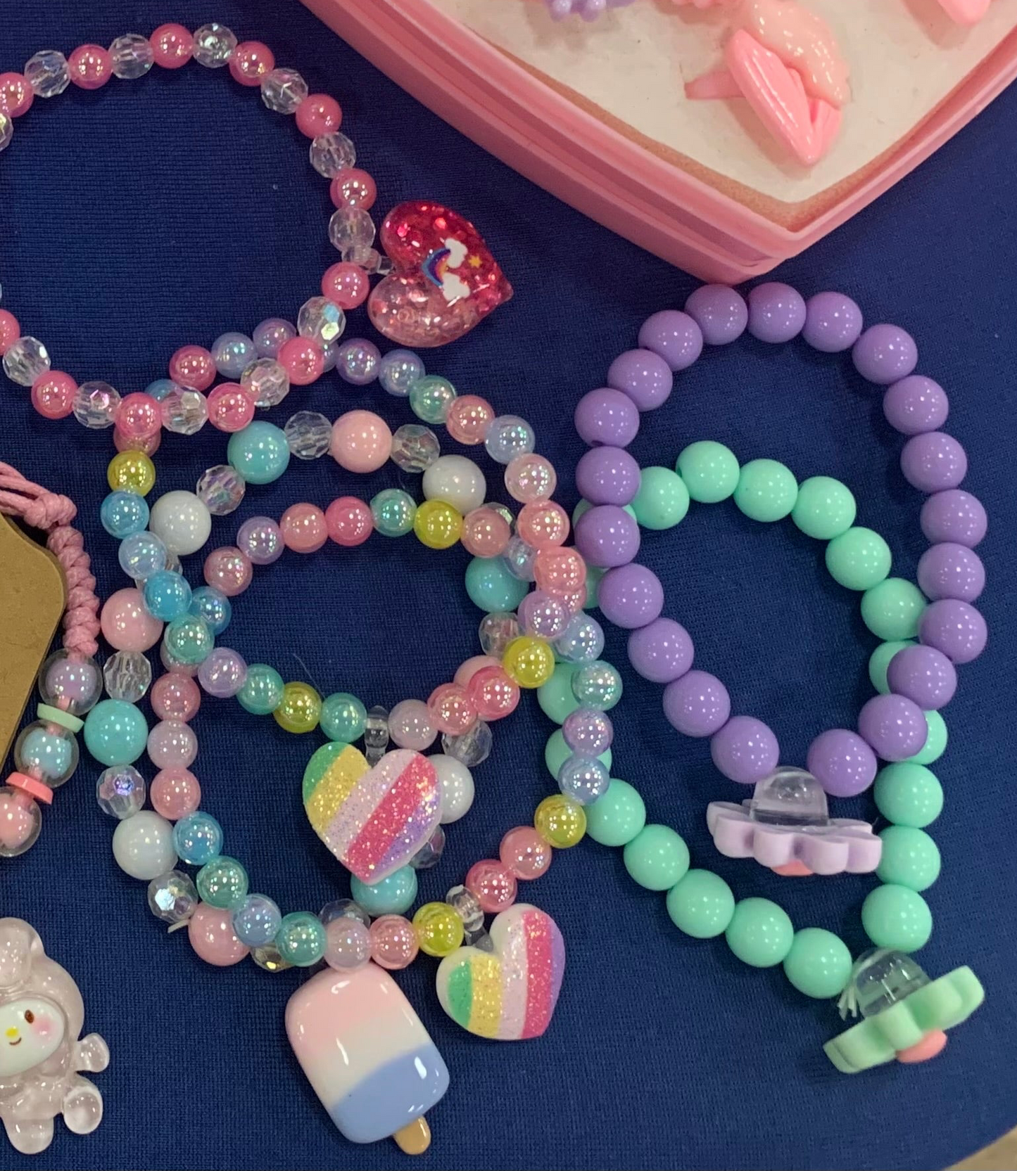 Colorful beaded kids bracelets with charms on a blue tablecloth