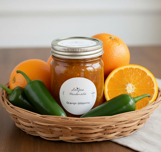 Lorjas Handmade 'Orange Jalapeno' pepper jelly in basket with fresh jalapeño peppers and oranges on woodgrain counter