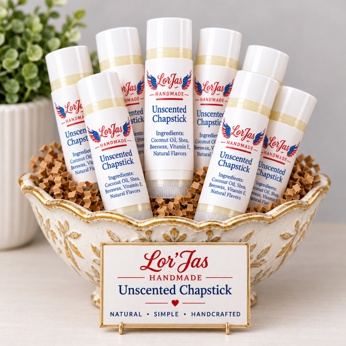 Tubes of Lor'jas Unscented Chapstick displayed inside a ceramic bowl. The white labels feature blue text detailing the all-natural ingredients.