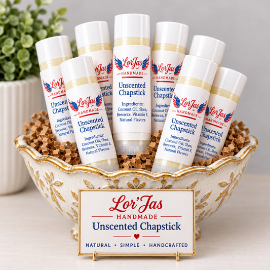 Tubes of Lor'jas Unscented Chapstick displayed inside a ceramic bowl. The white labels feature blue text detailing the all-natural ingredients.