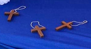 Three wooden crosses on keychains on a blue fabric table background